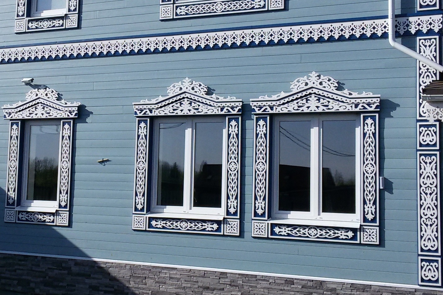 Классические белые резные наличники на голубом фасаде