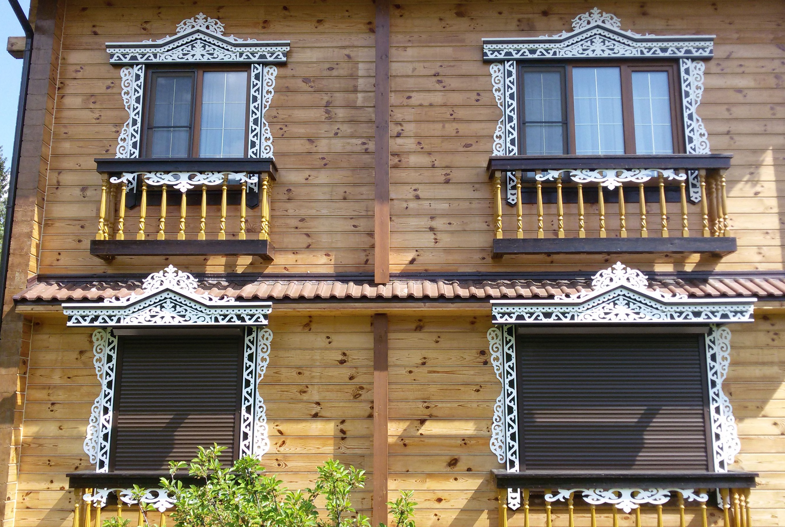 Белые резные наличники и карнизы на фасаде деревянного дома
