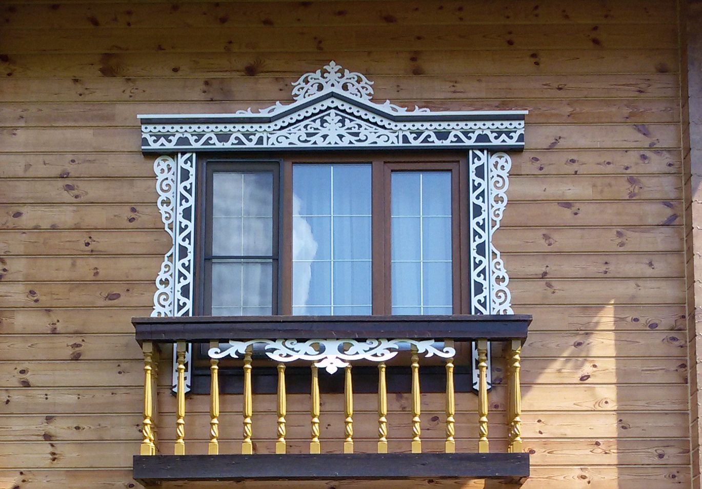 Белый резной наличник на фасаде деревянного дома